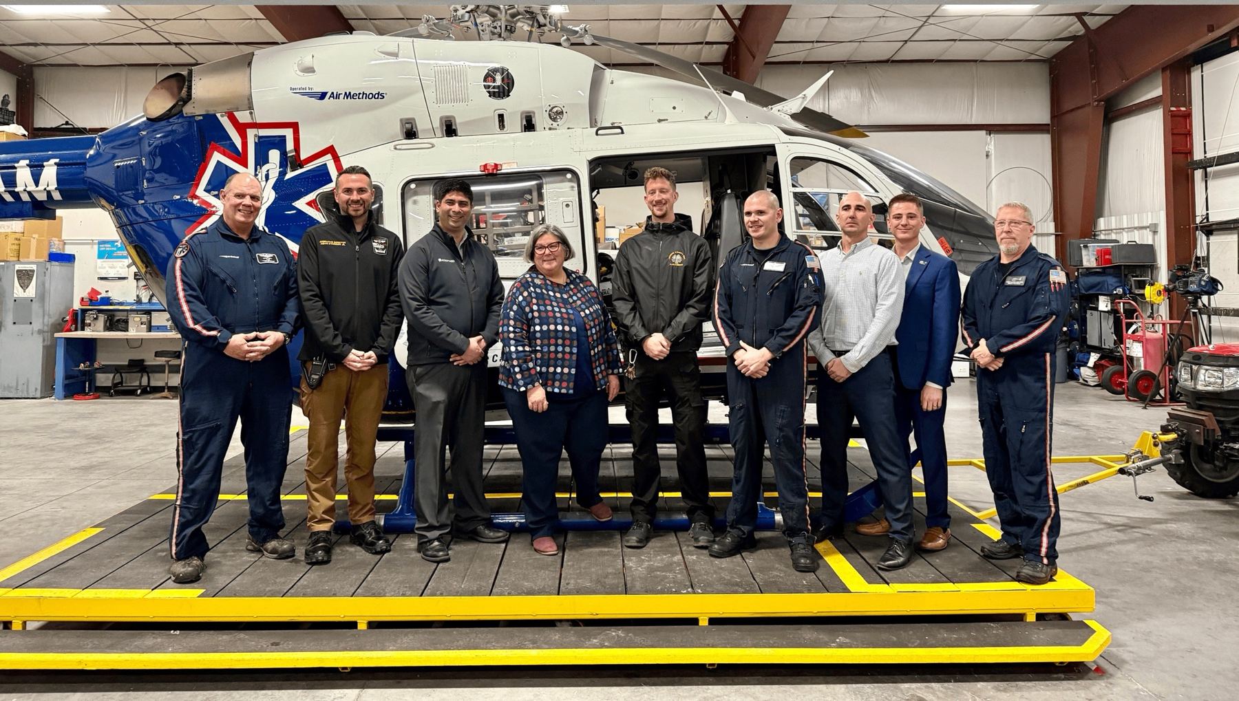 Greene County Paramedics leadership and partners standing in front of an air medical helicopter in its hangar