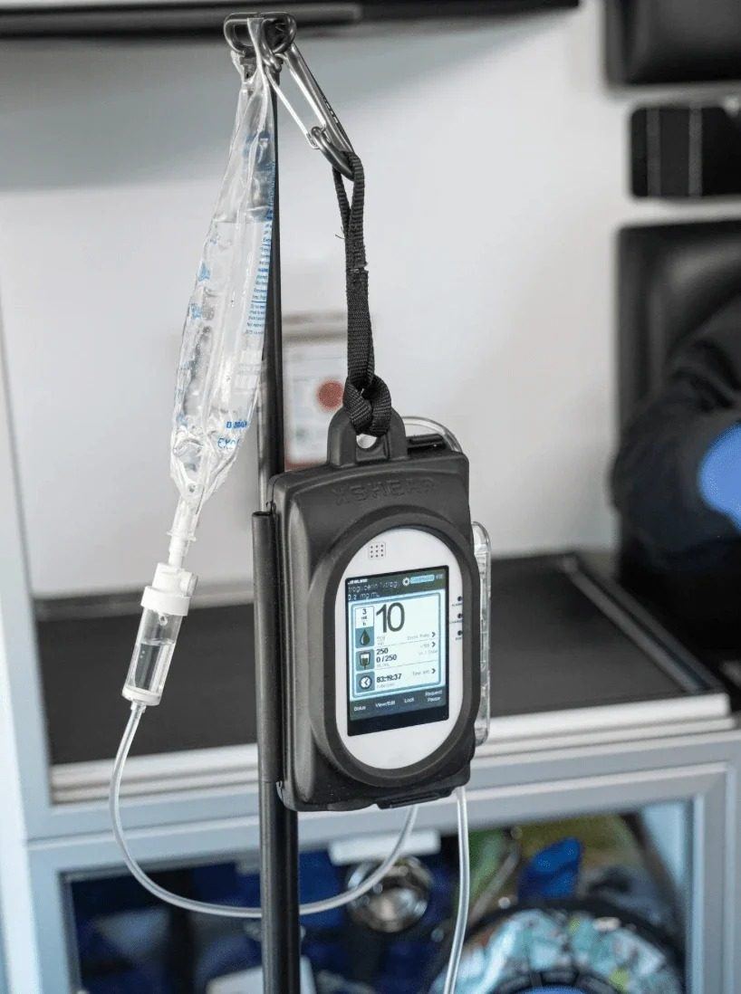 Sapphire infusion pump hanging from an IV pole with a medication bag, inside the truck