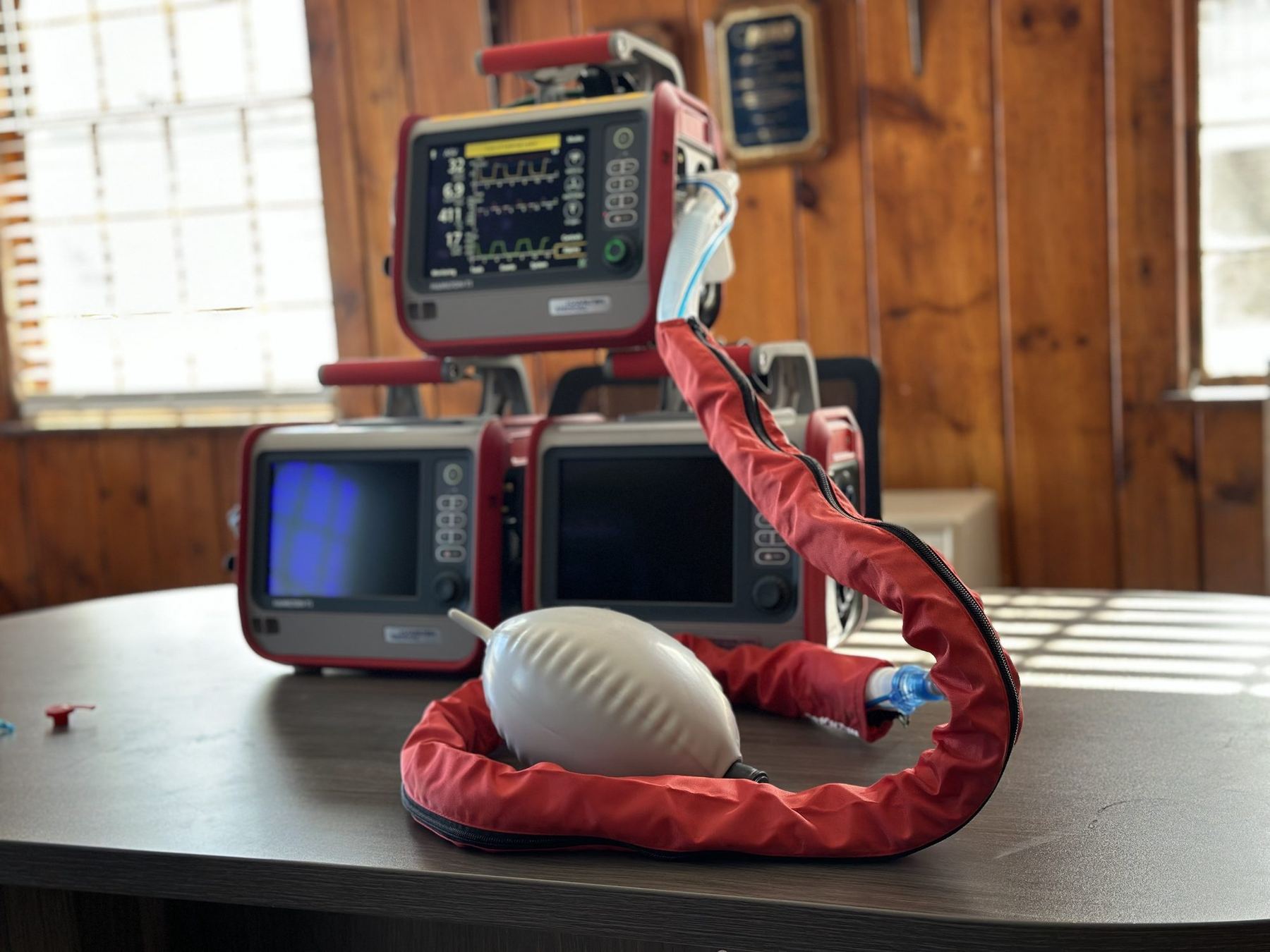 Three Hamilton T1 ventilators stacked on a table with a test lung