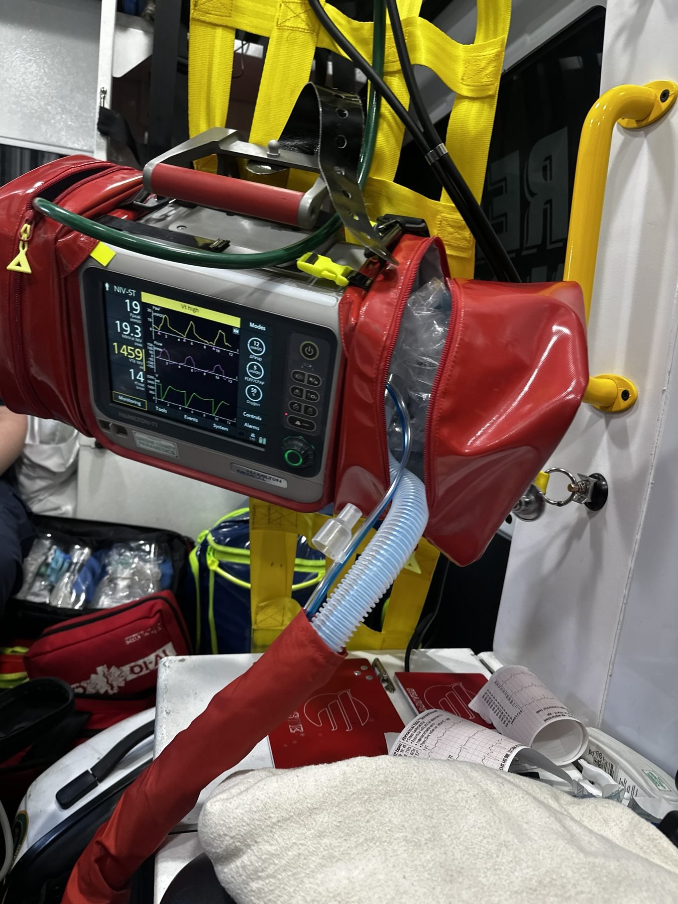 Hamilton T1 and cardiac monitor mounted at the head of a stretcher during transport in a small ambulance